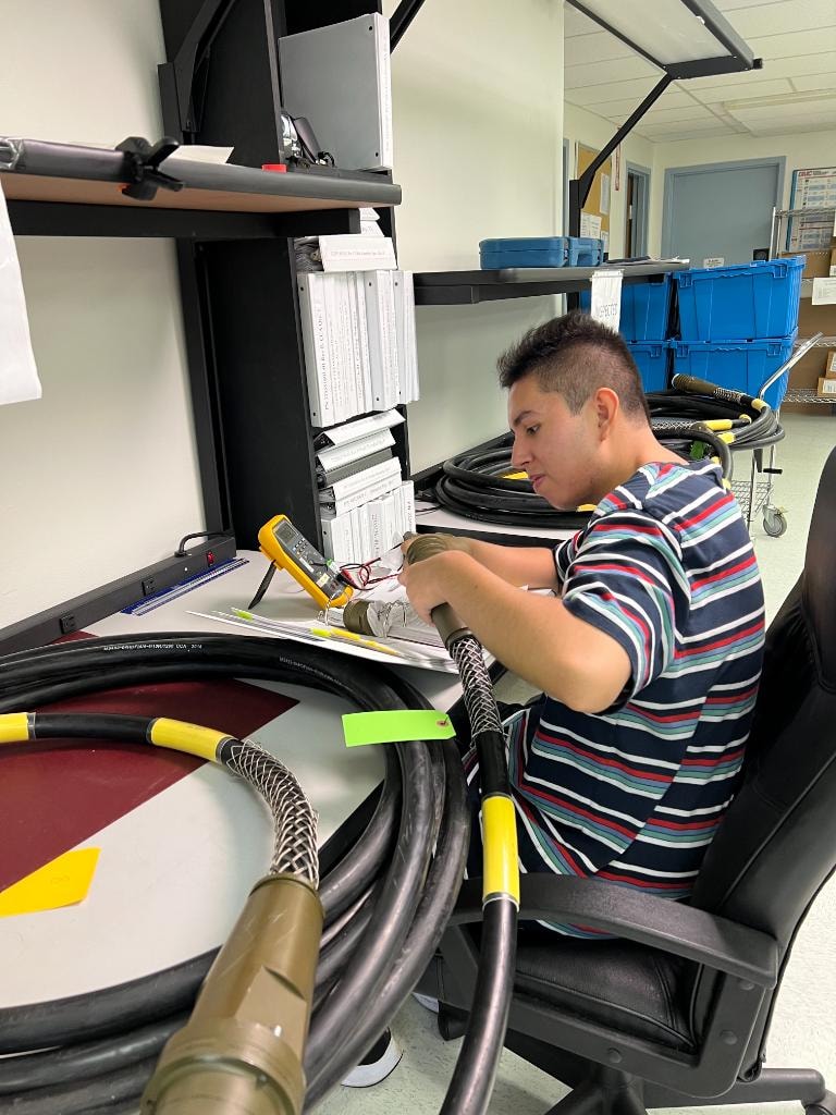 JIRACOR technician testing and measuring cables at a workbench in the Orlando production facility