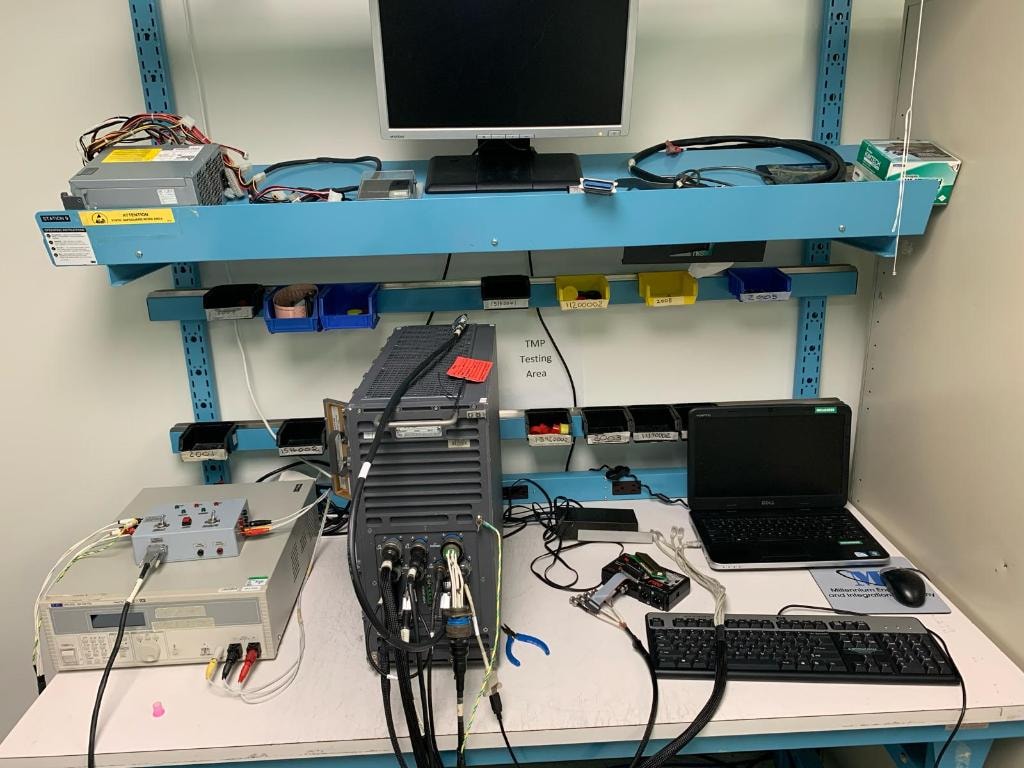 JIRACOR TMP testing area — workbench with test equipment, laptop, and electronic components under test