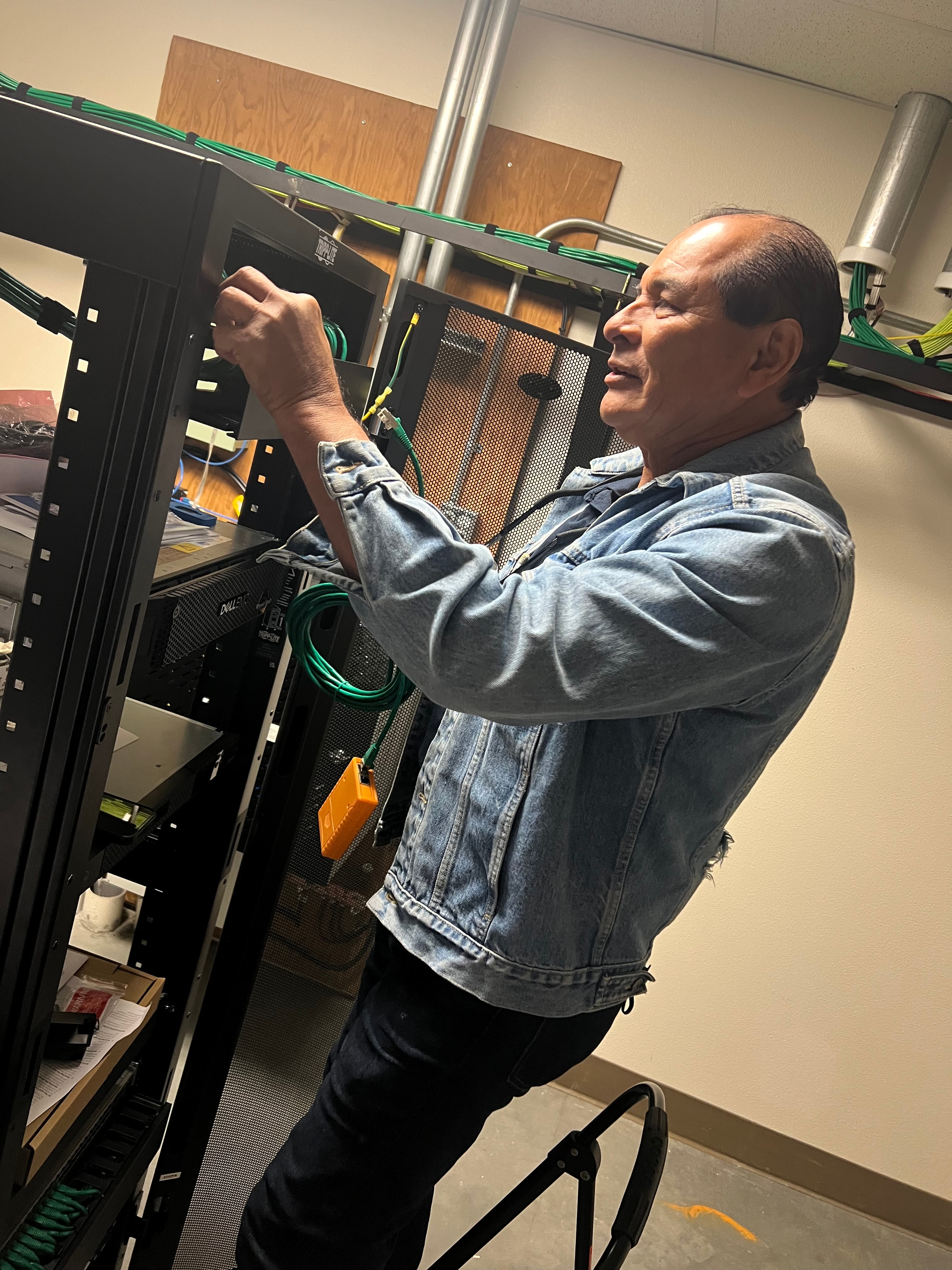 JIRACOR technician performing hands-on rack integration and structured cabling work as part of a training system technical refresh
